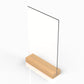 Angled side view of a wooden menu stand with a clear acrylic panel on top of a wooden base.